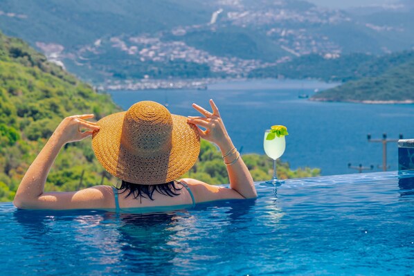 Una piscina al aire libre, sombrillas, sillones reclinables de piscina