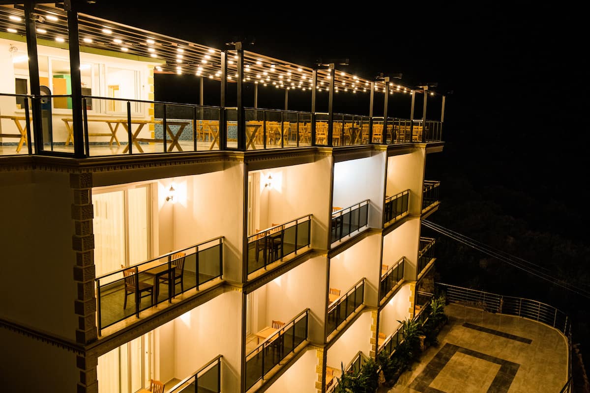 A multi-story hotel with balconies, outdoor seating, and string lights.