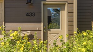 A house number 433, a front door with a glass panel, and yellow flowering plants in front.