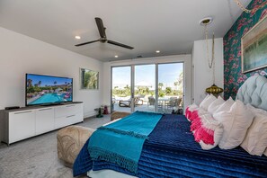 A bedroom with a bed, a television, a ceiling fan, and a view of the outdoors. - The Bird House - Swanky Poolside Paradise (Rancho Mirage)