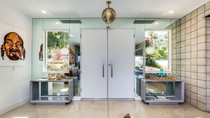 Een modern interieur met een glazen deuropening, een decoratieve plafondlamp en een glazen vitrinekast met een vaas.