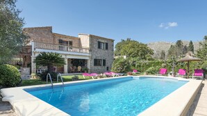 A swimming pool with lounge chairs, a stone building, and a mountain backdrop. - ASSUMPCIO. Pretty villa close to Pollensa (Pollensa)