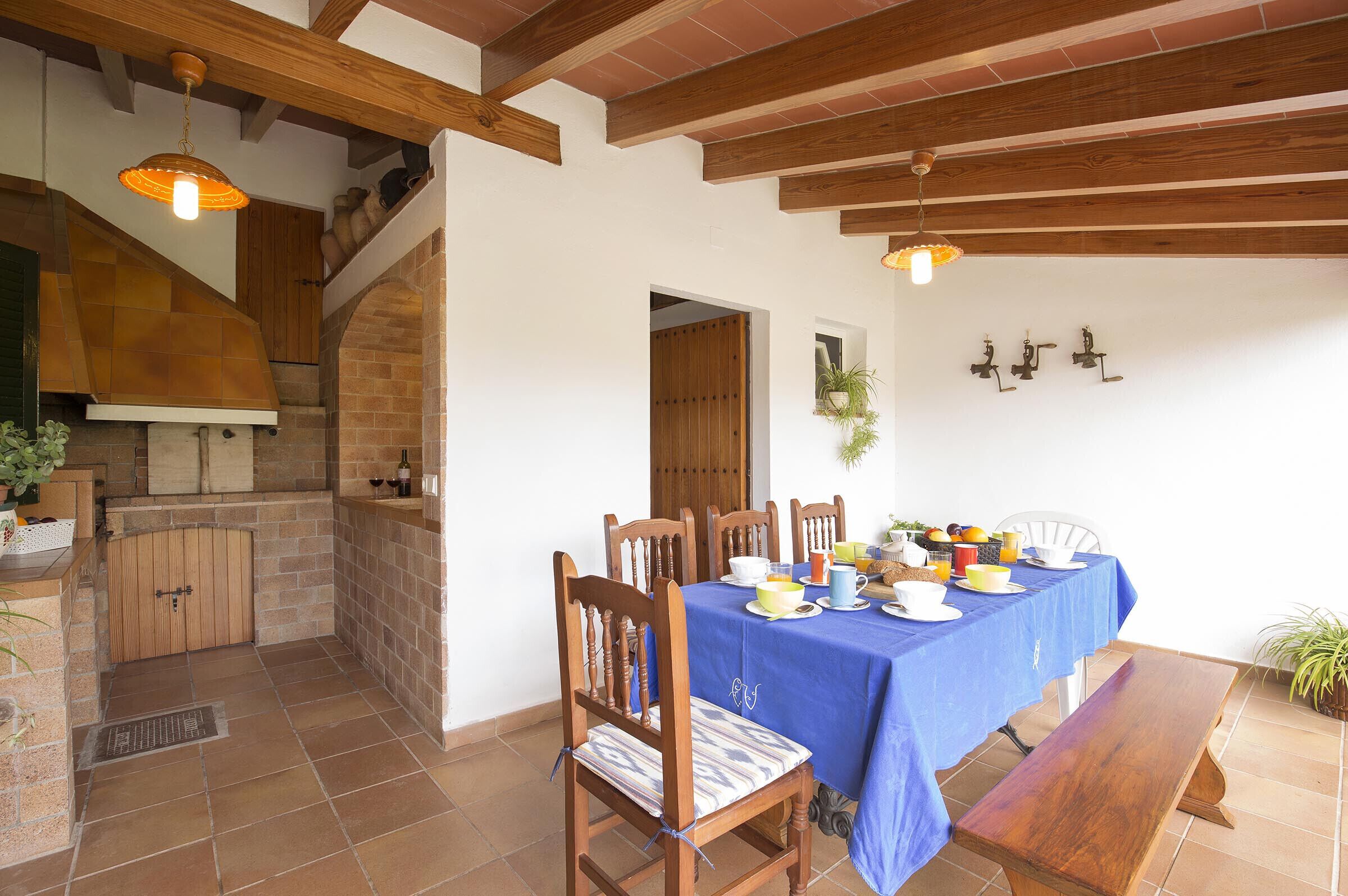 A dining area with a blue tablecloth, wooden chairs, and a bench.