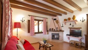 A living room with a red sofa, a wooden coffee table, a fireplace, and a television. - ASSUMPCIO. Pretty villa close to Pollensa (Pollensa)