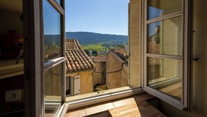 Una ventana abierta con vistas a un pueblo y colinas.