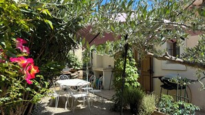Un patio con mobiliario exterior, una pérgola y un jardín con plantas.