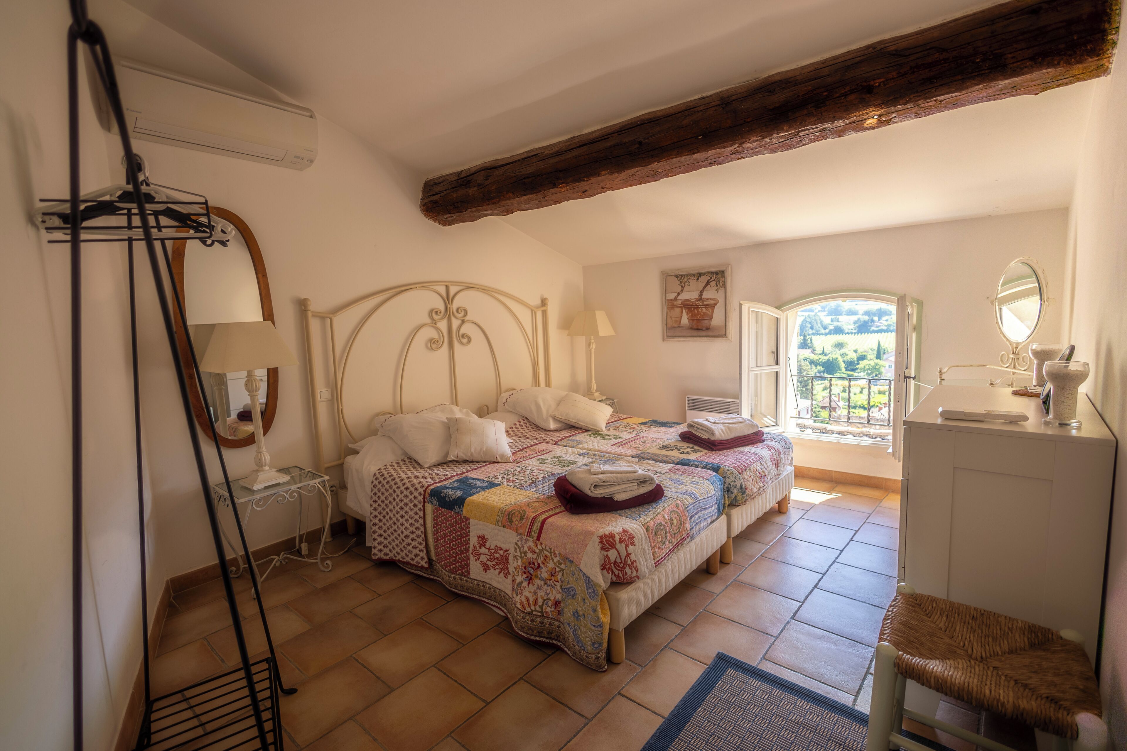 Une chambre à coucher comprenant un lit, des tables de chevet, une chaise, une fenêtre et une vue sur l’extérieur.