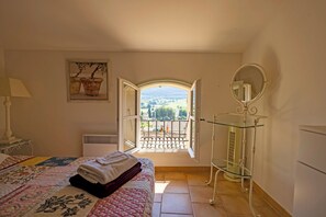 A bedroom with a bed, a window, a radiator, a mirror, and a painting. - La Maison des Pèlerins (Sablet)