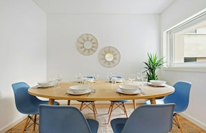 A dining area with a round table, blue chairs, and decorative wall mirrors. - Merces 2 BDR Apt Bairro Alto (Lisboa)