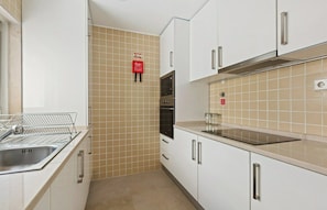 A kitchen with white cabinets, a stainless steel sink, and a tiled backsplash. - Merces 2 BDR Apt Bairro Alto (Lisboa)