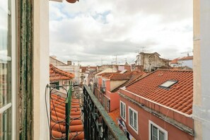 A view of a cityscape with red-tiled roofs, a balcony with a metal railing, and a cloudy sky. - Bairro Alto Attic Apartment With Balcony (Lisboa)