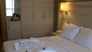 A hotel room with a bed, a nightstand, a lamp, a wardrobe, and a window. - Turunc Bay Conti Boutique Hotel (Marmaris)