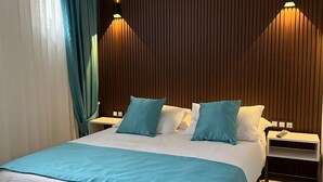 A modern bedroom with a large bed, two bedside tables, and a wooden headboard. - My Dream Bozcaada (Bozcaada)