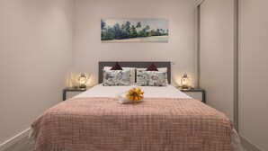 A neatly made bed with a textured blanket, two bedside lamps, and a floral arrangement on the bed. - ANGEL'S SUNSET T2 ESTRITO DA CALHETA (Estreito da Calheta)