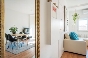 Un salon moderne comprenant un canapé, un coin repas avec une table et des chaises, un téléviseur et une plante.