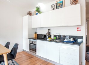 Uma cozinha moderna com armários brancos, forno embutido e uma pia.