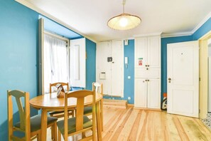 Ein Zimmer mit Esstisch, Stühlen, einer Pendelleuchte und einem Kleiderschrank.