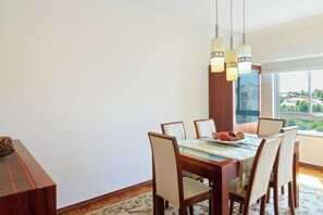 A dining area with a wooden table, six chairs, and a fruit plate.