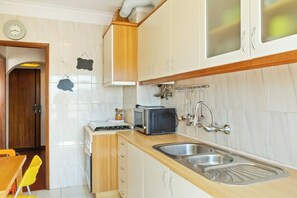A compact kitchen with a microwave, toaster, and double sink.