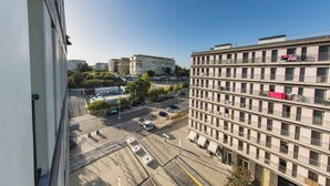 A multi-story building with balconies, a parking lot, and a clear sky.