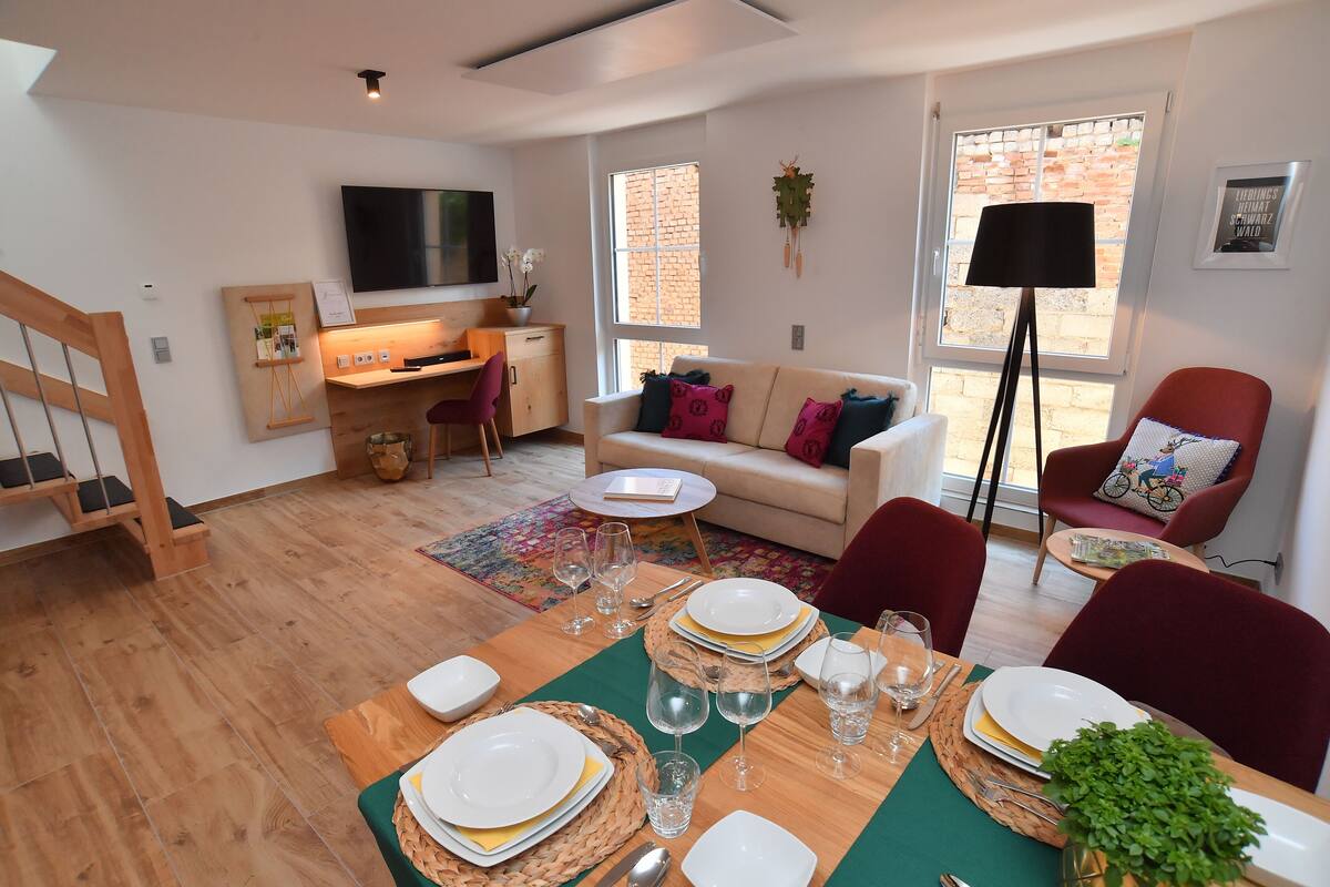 A modern living room with a dining area set for a meal.