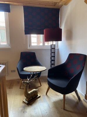 A room with two blue armchairs, a small round table, a red floor lamp, and a wooden sculpture on the floor. - Der Ochsen (Kappel-Grafenhausen)