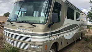 Een ruime camper met een gestroomlijnd ontwerp, met een opvallende voorgrille en zijstrepen.