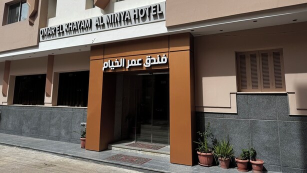De gevel van Hotel Omar El Khamam Al Minya, met een bord in zowel Arabisch als Engels.