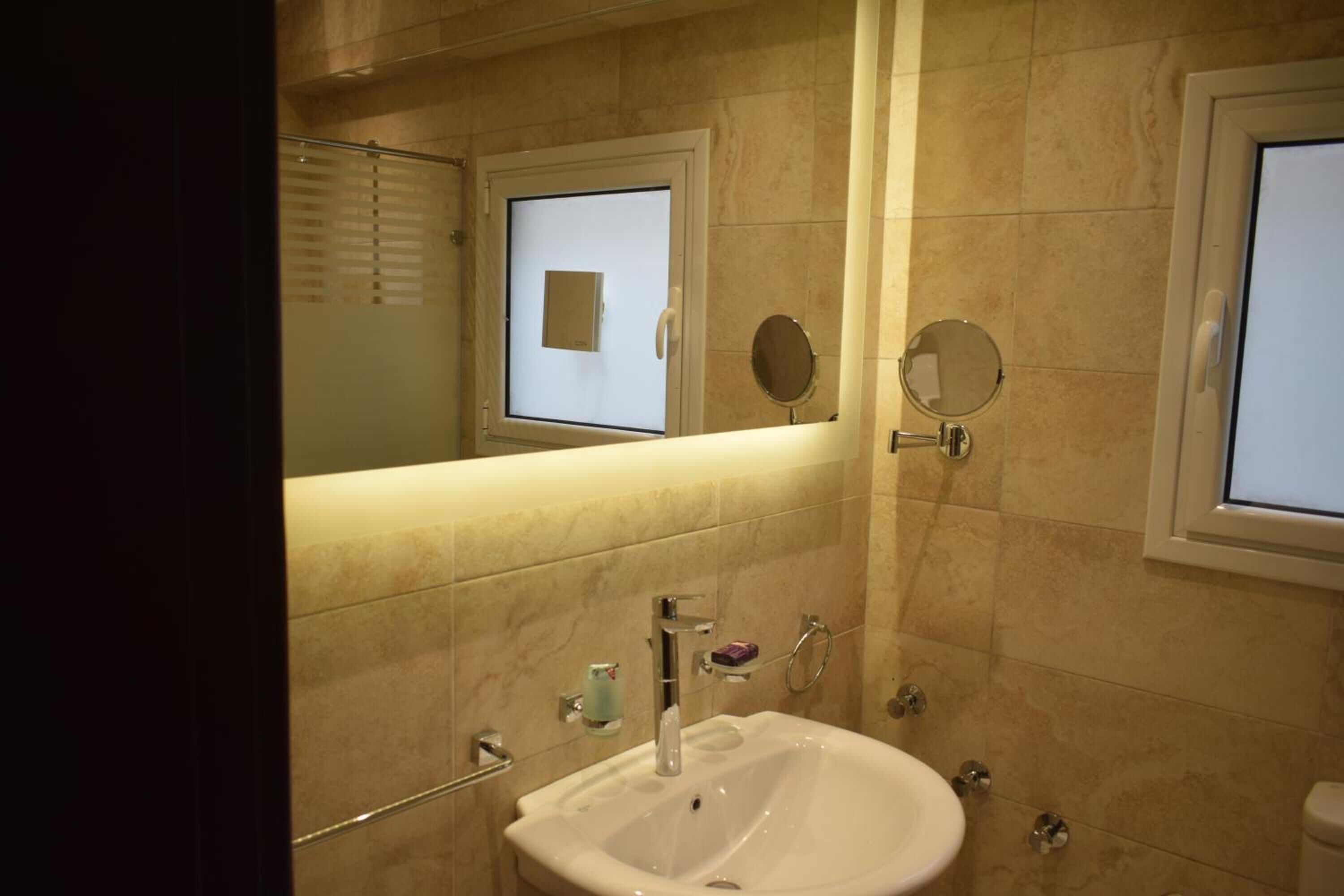 Un baño con lavamanos, espejo y ventana.