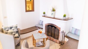 A cozy living room with a fireplace, a sofa, a chair, and a small coffee table. - Estate4home - GOAT PATH (Positano)