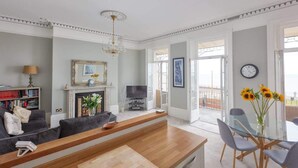 Una sala de estar con sofá, televisor, chimenea y comedor con sillas y una mesa.