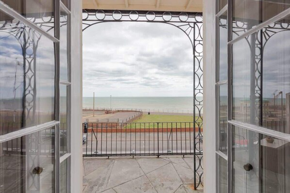 A balcony with a view of the beach and a fence.