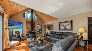 A spacious living room with a large leather sofa, a fireplace, and a stone wall. - Exquisite Vacation Home with Hot Tub, EV Charger (Arnold)