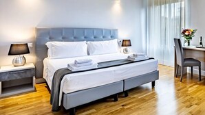 A modern hotel room with a large bed, bedside tables, a desk, and a chair.