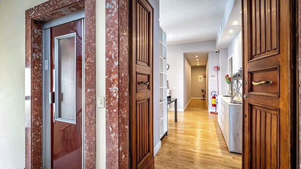 A hallway with wooden doors, a marble wall, and a wooden floor.