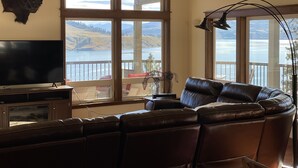 A living room with a large window, a mounted buffalo head, a leather sofa, and a television.
