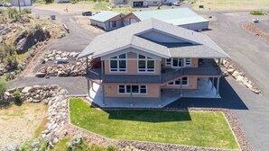A multi-story house with a large front lawn and a driveway.
