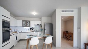 Eine moderne Küche mit weißen Schränken, einem Edelstahlkühlschrank und einem Essbereich mit Tisch und Stühlen.