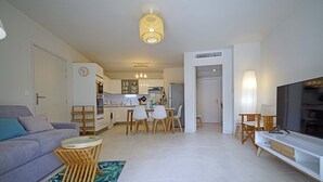 Ein modernes Wohnzimmer mit einer Couch, einem Fernseher und einem Essbereich mit Stühlen und einem Tisch.