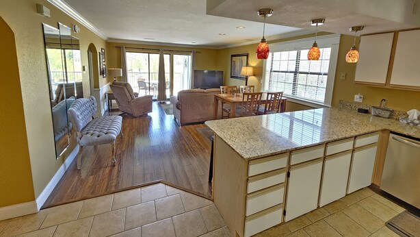 A spacious living area with a large sofa, a dining table, and a kitchen with a granite countertop and wooden cabinets. - Luxury Getaway Branson Suite at the Greens at Thousand Hills! Great Rates!  (Branson)