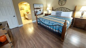 A bedroom with a wooden bed, a painting on the wall, and a door leading to another room. - Luxury Getaway Branson Suite at the Greens at Thousand Hills! Great Rates!  (Branson)