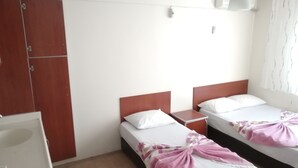 A hotel room with two single beds, wooden headboards, white bedding, a small bedside table, and a wardrobe. - Elmas Motel (Marmara)