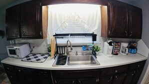 Una cocina compacta con pileta integrada, microondas y cafetera.