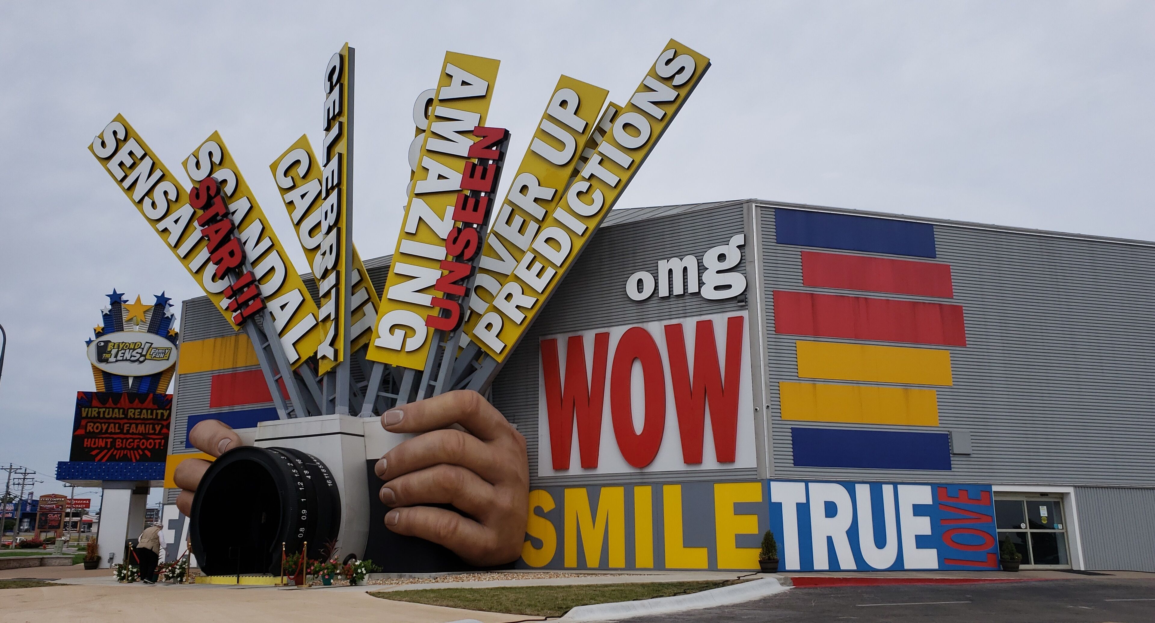 A building with a large hand graphic and various signs including 'WOW SMILE TRUE LOVE'.
