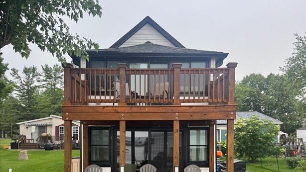 A two-story house with a balcony, outdoor seating area, and a fire pit. - Lakefront Cottage on Portage Lake and the Huron River Chain of Lakes (Pinckney)