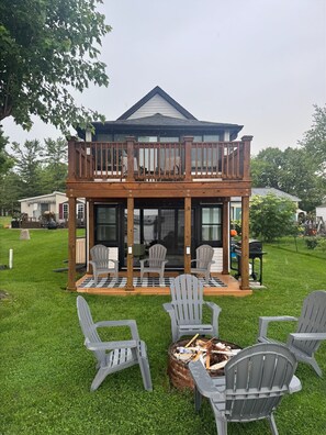 A two-story house with a balcony, outdoor seating area, and a fire pit. - Lakefront Cottage on Portage Lake and the Huron River Chain of Lakes (Pinckney)