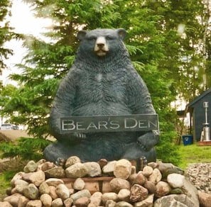 Discover the charming Bear's Den, a unique landmark in a serene natural setting surrounded by trees and a scenic backdrop.