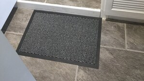 A doorway leading to a room with a wooden floor, a black doormat, and a chair with a cushion. - Clean & Comfortable room near beaches, Eden, Heligan and Charlestown (St Austell)
