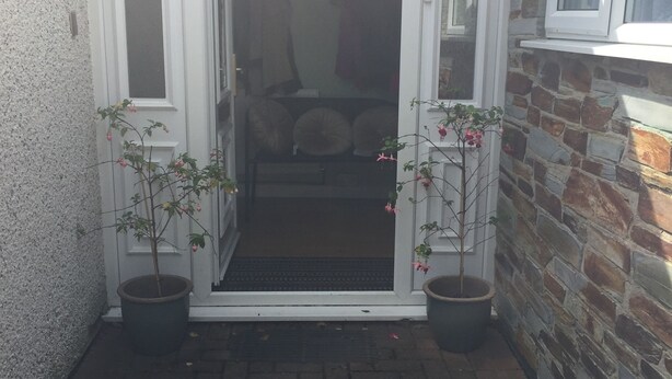 A narrow brick pathway leading to a white door with glass panels, flanked by potted plants. - Clean & Comfortable room near beaches, Eden, Heligan and Charlestown (St Austell)