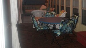Un patio interior con mesa y sillas, luces colgantes y un ventilador de techo.